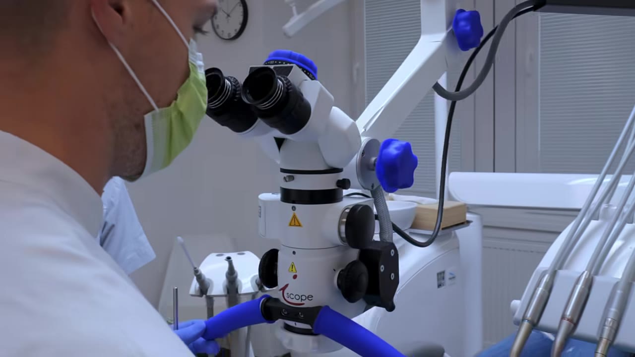 Zubný lekár pri ošetrení pod dentálnym mikroskopom